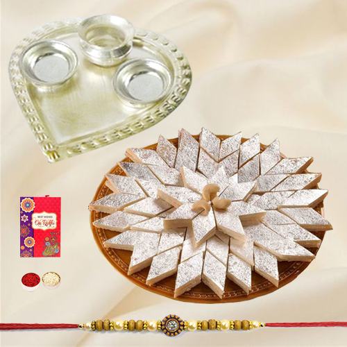 Delicious Kaju Katli and Stylish and Trendy looking Silver Plated Paan Shaped Puja Aarti Thali along Rakhi, Roli, Tilak and Chawal Delicious Kaju Katli and Stylish and Trendy looking Silver Plated Paan Shaped Puja Aarti Thali along Rakhi, Roli, Tilak and Chawal